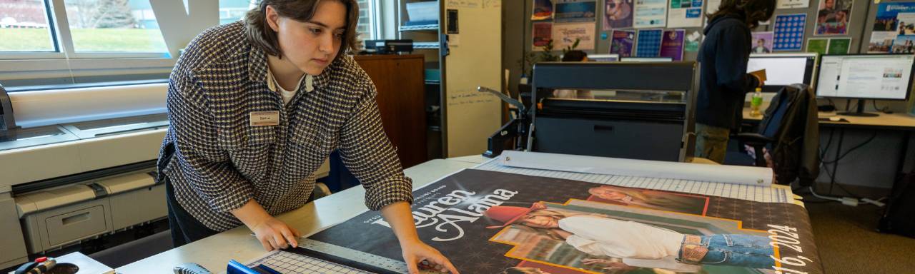 A graphic designer working on printing and cutting a poster